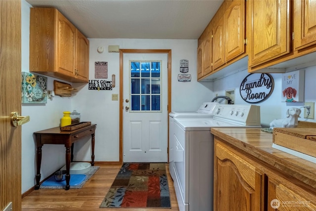 laundry area with cabinets, separate washer and dryer, and light hardwood / wood-style floors