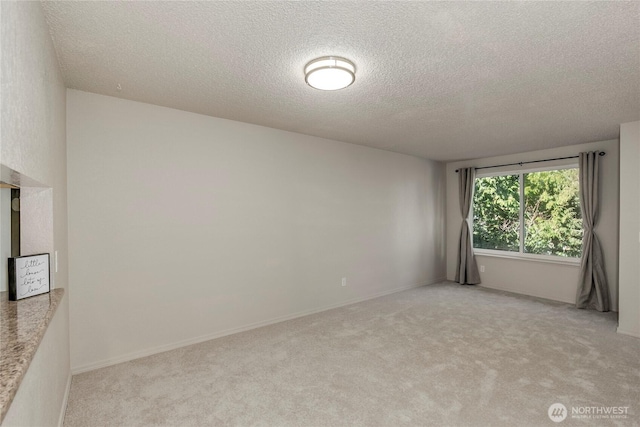 spare room with light carpet and a textured ceiling