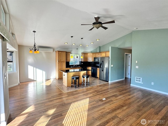 kitchen with a center island, hanging light fixtures, dark countertops, and black appliances