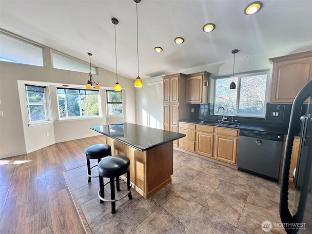 kitchen with a center island, dark countertops, vaulted ceiling, a sink, and dishwasher