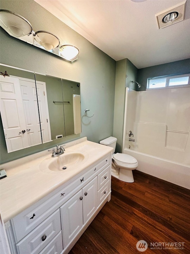 full bath with visible vents, toilet, shower / tub combination, wood finished floors, and vanity