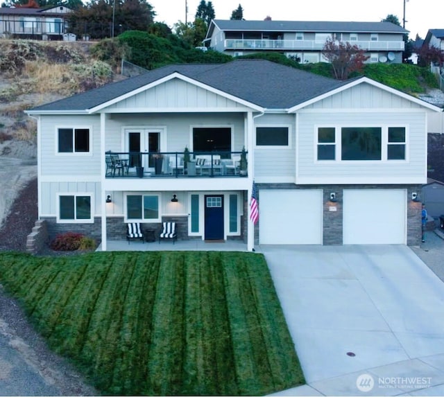 view of front of property with board and batten siding, a balcony, stone siding, driveway, and a front lawn