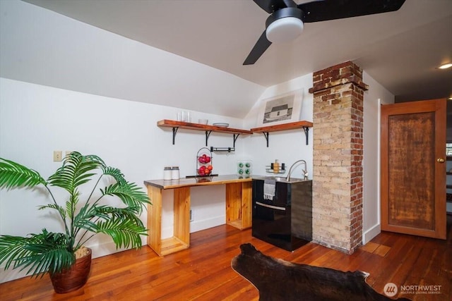 kitchen featuring dark wood-type flooring, ceiling fan, vaulted ceiling, and decorative columns