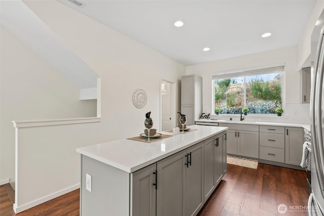 kitchen with dark hardwood / wood-style flooring, sink, gray cabinets, and an island with sink