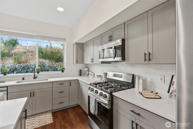 kitchen with gray cabinetry, sink, tasteful backsplash, and stainless steel appliances