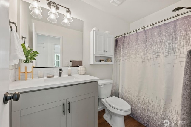 bathroom featuring tasteful backsplash, vanity, hardwood / wood-style floors, and toilet