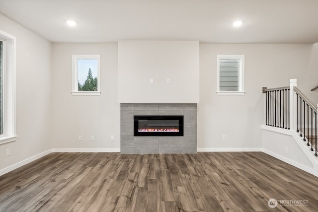 unfurnished living room with a tiled fireplace and wood-type flooring