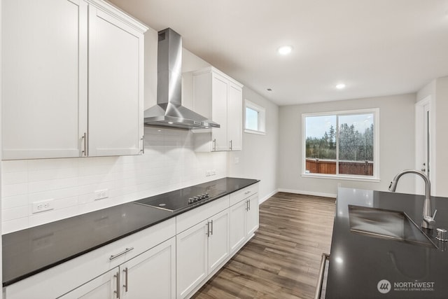 kitchen featuring dark hardwood / wood-style floors, white cabinetry, decorative backsplash, black electric stovetop, and wall chimney exhaust hood