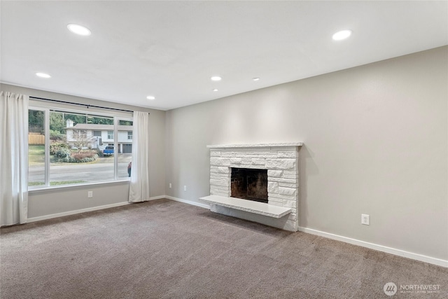 unfurnished living room featuring a stone fireplace and carpet floors