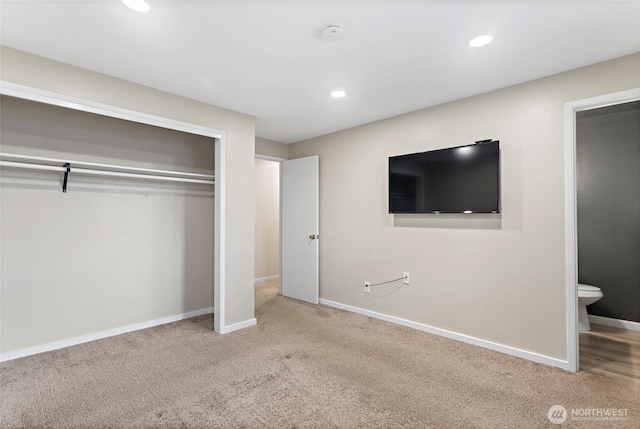 unfurnished bedroom featuring light colored carpet, a closet, and ensuite bathroom