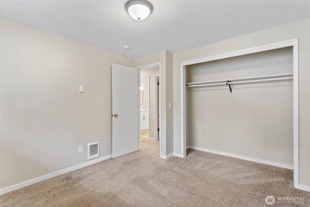 unfurnished bedroom with light carpet and a closet