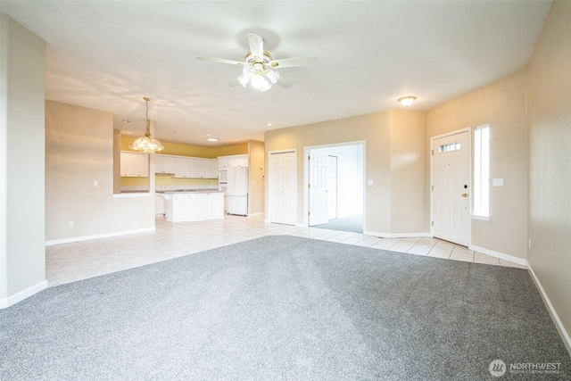 unfurnished living room featuring ceiling fan with notable chandelier and light colored carpet