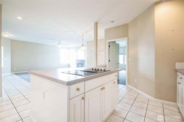 kitchen with light tile patterned floors, ceiling fan, white cabinetry, black electric stovetop, and a kitchen island