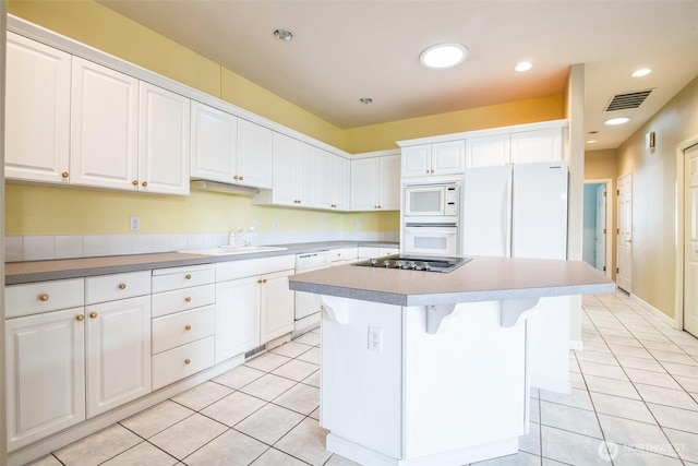 kitchen featuring a kitchen island, sink, white cabinets, and white appliances