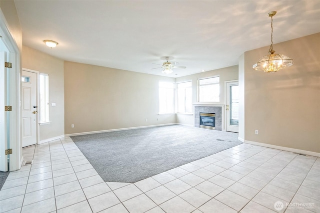 unfurnished living room featuring ceiling fan with notable chandelier, light carpet, and a fireplace