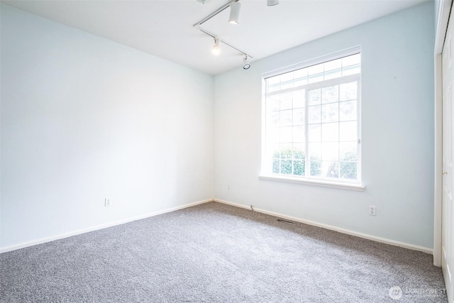 empty room with carpet flooring and track lighting