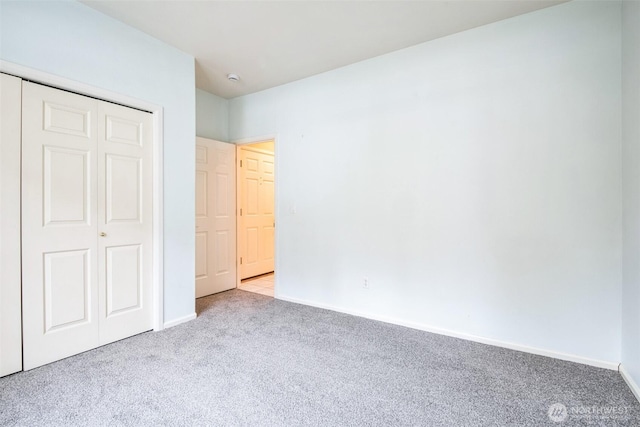 unfurnished bedroom featuring light carpet and a closet