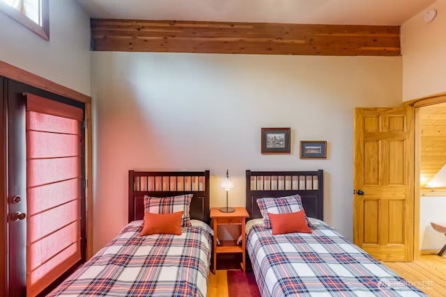 bedroom featuring beamed ceiling and wood finished floors