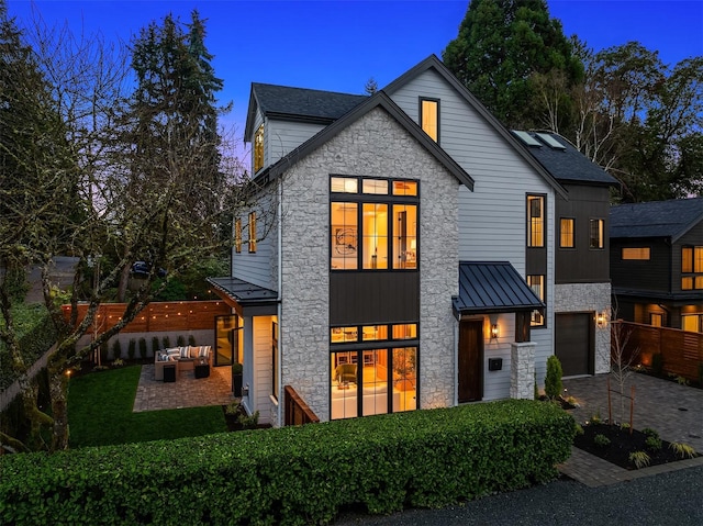 view of front facade featuring an outdoor living space, a patio area, and a garage