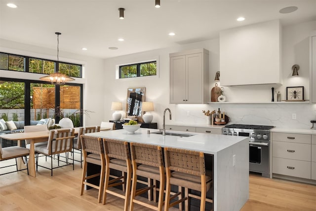 kitchen with sink, a breakfast bar area, stainless steel range, and decorative light fixtures