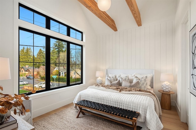 bedroom with beam ceiling, high vaulted ceiling, and light wood-type flooring