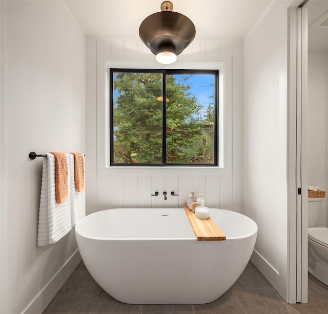 bathroom with a bath, tile patterned floors, and toilet