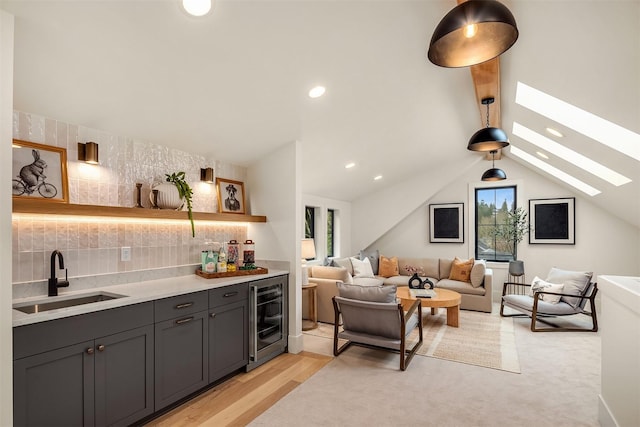 living room featuring wine cooler, lofted ceiling with skylight, light wood-type flooring, and wet bar