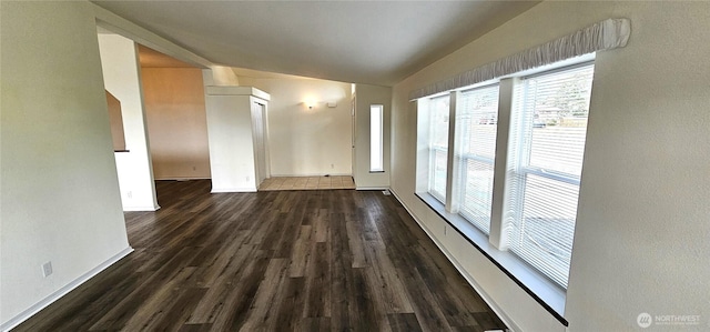 spare room featuring dark wood-type flooring and vaulted ceiling