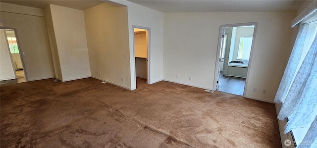 unfurnished bedroom with ensuite bathroom, carpet, a spacious closet, and a closet