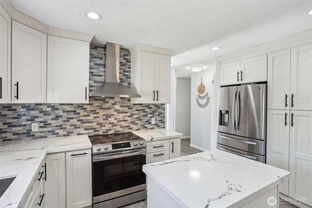 kitchen featuring white cabinets, wall chimney range hood, appliances with stainless steel finishes, and decorative backsplash