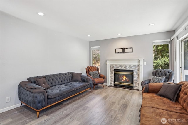 living room featuring recessed lighting, baseboards, wood finished floors, and a stone fireplace