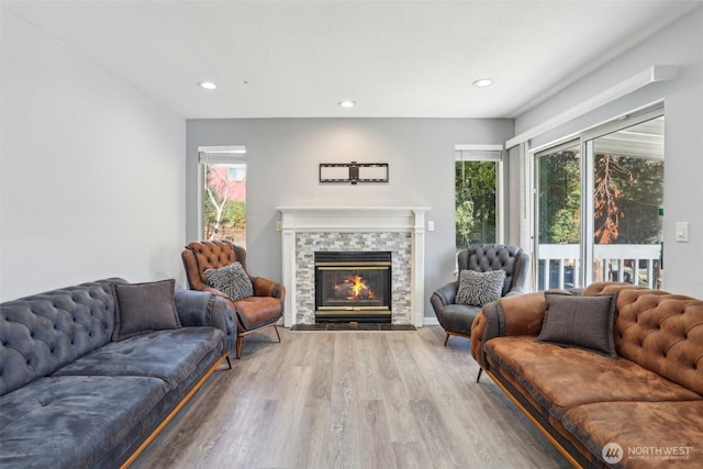 living room with recessed lighting, wood finished floors, and a stone fireplace