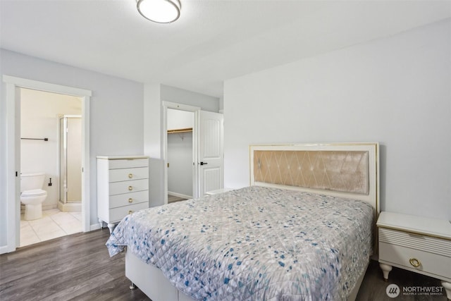 bedroom featuring baseboards, wood finished floors, ensuite bathroom, a spacious closet, and a closet