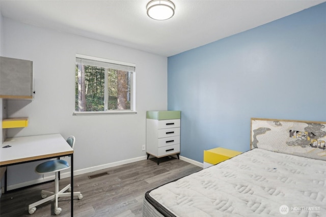 bedroom featuring visible vents, baseboards, and wood finished floors