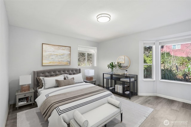 bedroom with multiple windows, baseboards, and wood finished floors