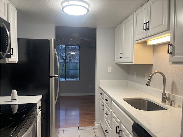 kitchen featuring white cabinetry, light stone countertops, sink, and light tile patterned flooring