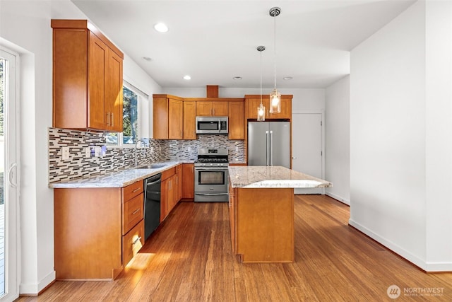 kitchen with pendant lighting, tasteful backsplash, sink, a center island, and stainless steel appliances