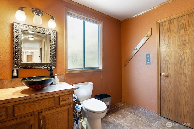 bathroom with ornamental molding, vanity, toilet, and tile patterned floors