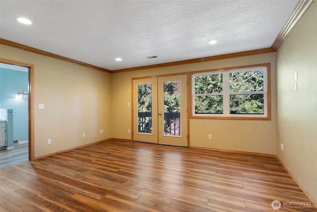 unfurnished room featuring french doors, visible vents, a textured ceiling, and wood finished floors