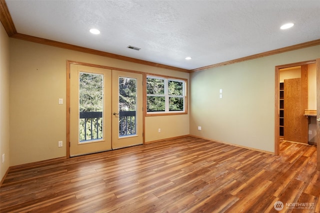 unfurnished room with a healthy amount of sunlight, visible vents, wood finished floors, and french doors