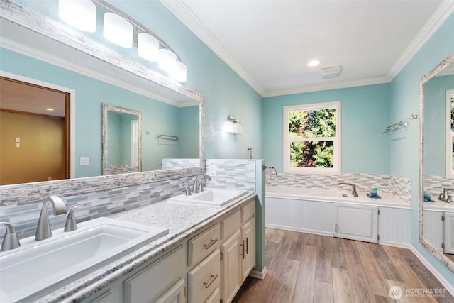 bathroom featuring a bath, crown molding, double vanity, and a sink