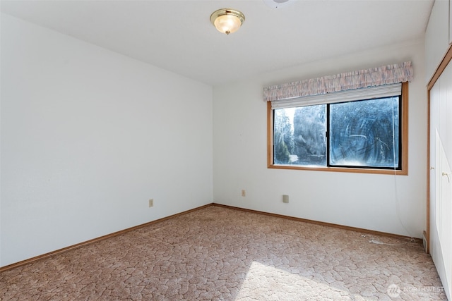 empty room featuring carpet and baseboards