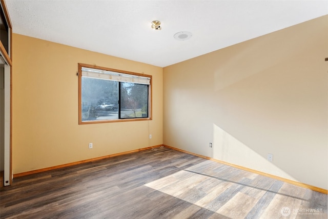 unfurnished room featuring dark wood finished floors and baseboards