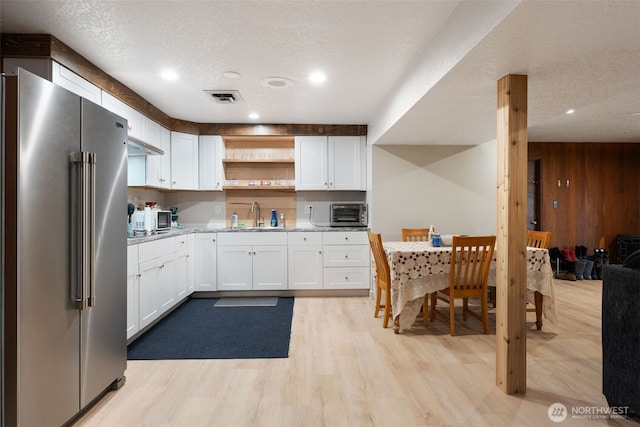 kitchen with white cabinets, visible vents, high end refrigerator, and open shelves