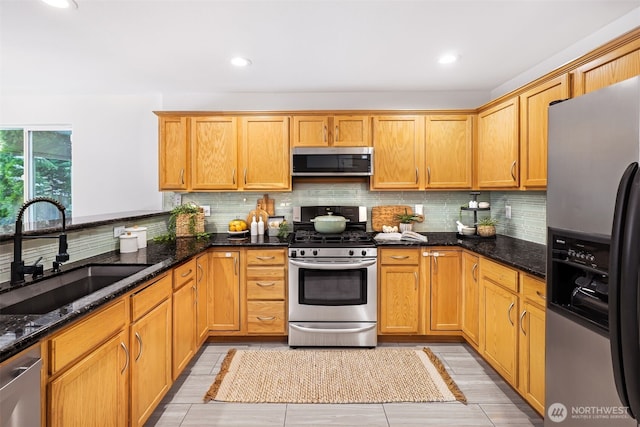 kitchen with tasteful backsplash, sink, dark stone counters, and appliances with stainless steel finishes