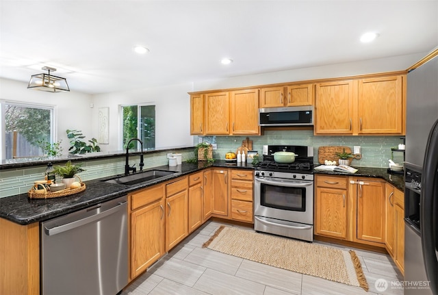 kitchen with sink, dark stone countertops, backsplash, kitchen peninsula, and stainless steel appliances