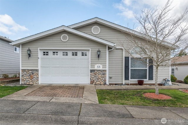 view of front of property featuring driveway, stone siding, and an attached garage