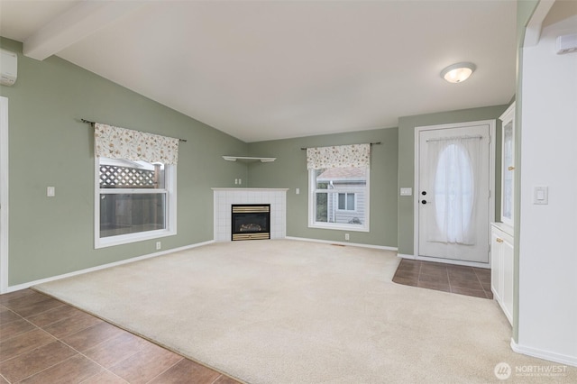 unfurnished living room featuring lofted ceiling with beams, a tiled fireplace, baseboards, and carpet flooring