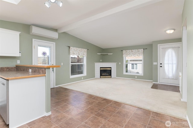 kitchen with white cabinets, a tile fireplace, lofted ceiling with beams, a wall mounted air conditioner, and carpet flooring