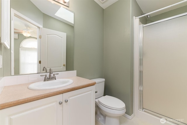 bathroom featuring ceiling fan, a stall shower, vanity, and toilet